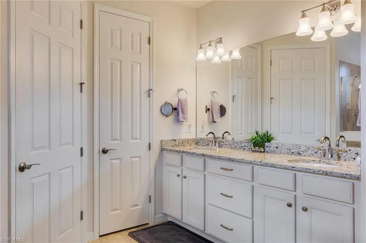 Bathroom featuring double vanity, a chandelier, and a tile shower