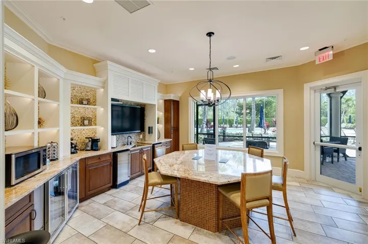 Kitchen featuring hanging light fixtures, light stone countertops, a chandelier, appliances with stainless steel finishes, and recessed lighting