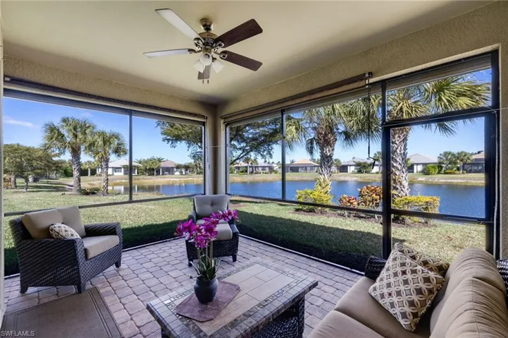 Sunroom with ceiling fan, a residential view, and a water view