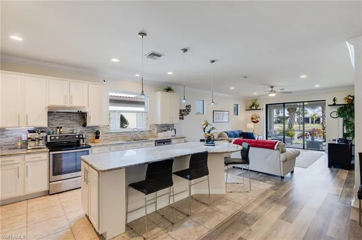 Kitchen featuring appliances with stainless steel finishes, pendant lighting, a kitchen island, ornamental molding, and a kitchen breakfast bar