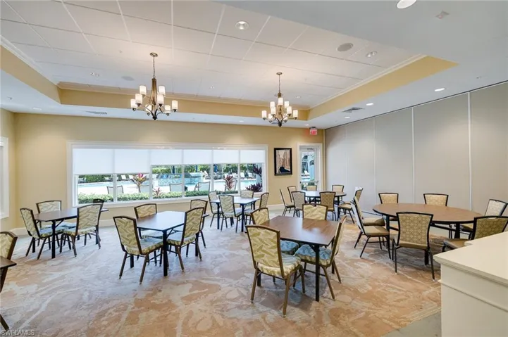 Dining space with ornamental molding, a raised ceiling, a chandelier, recessed lighting, and light colored carpet