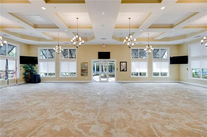 Unfurnished living room featuring a towering ceiling, coffered ceiling, beam ceiling, a chandelier, and recessed lighting
