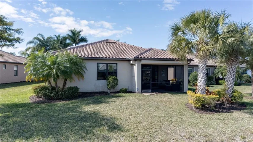 Rear view of house featuring stucco siding, a yard, a tiled roof, and a sunroom