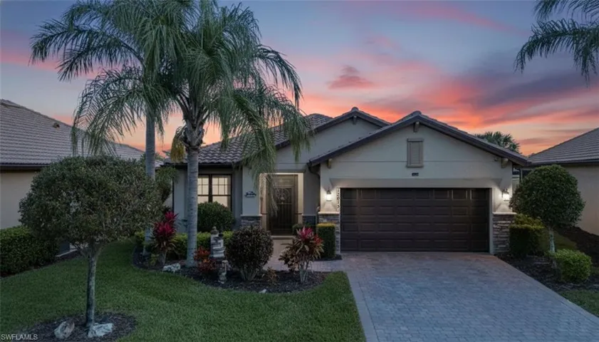 View of front of house featuring stucco siding, stone siding, a front lawn, and driveway