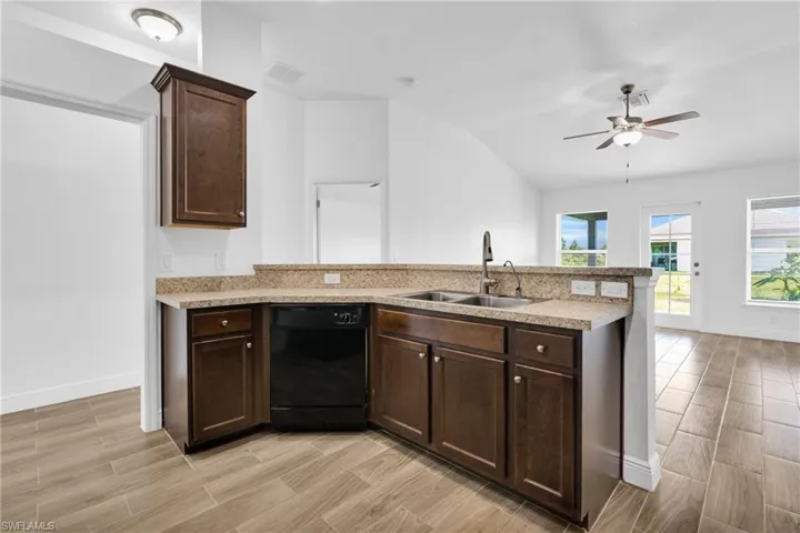 Kitchen featuring dishwasher, a peninsula, light wood finished floors, light countertops, and lofted ceiling