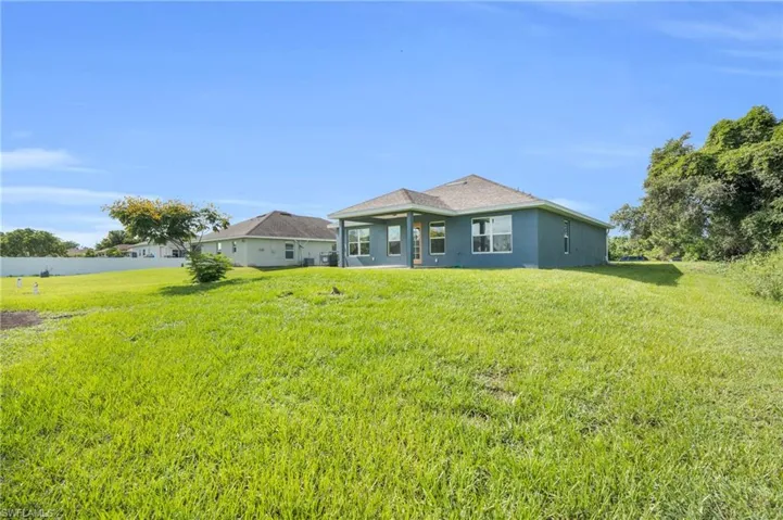 Rear view of property featuring a lawn and stucco siding