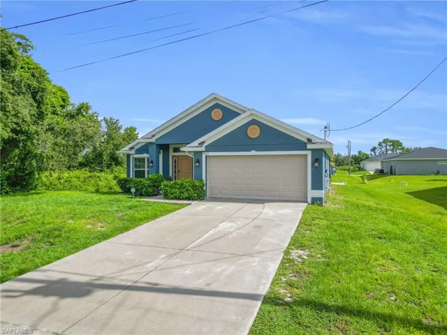 View of front of property with stucco siding, a garage, a front yard, and concrete driveway