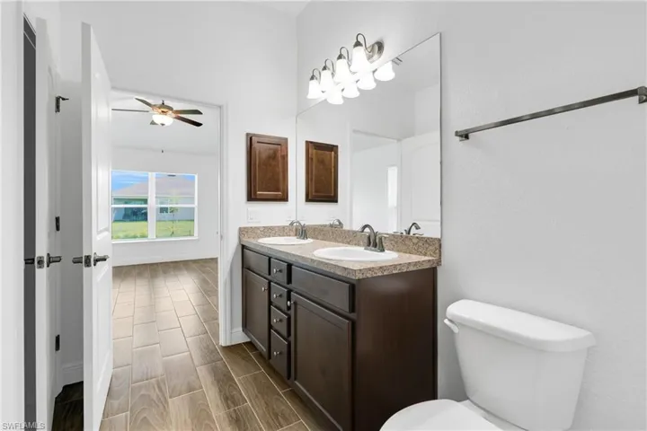 Full bath featuring double vanity, a ceiling fan, and wood tiled floors