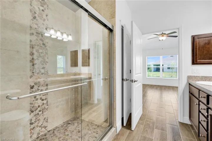 Full bath featuring vanity, a shower stall, ceiling fan, and wood finish floors