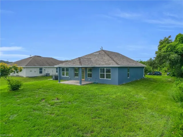 Back of house featuring a lawn, a patio, and stucco siding