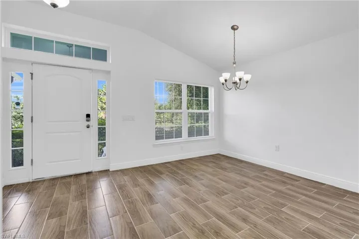 Entryway featuring a chandelier, vaulted ceiling, and wood finished floors