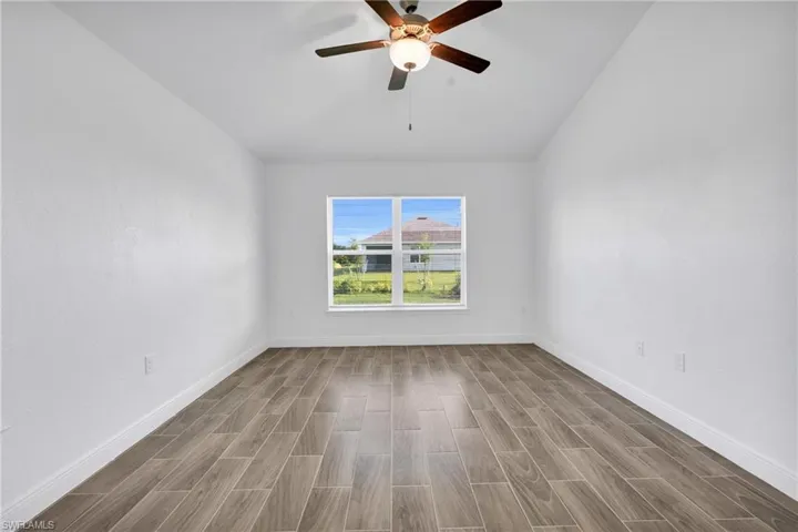 Spare room with wood finished floors, a ceiling fan, and lofted ceiling