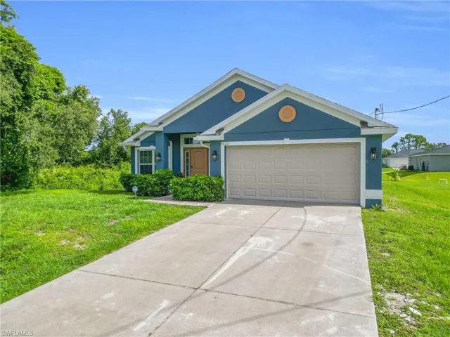 Ranch-style house with stucco siding, a front lawn, concrete driveway, and a garage