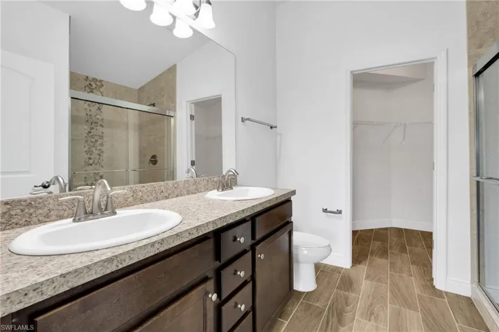 Full bath featuring a spacious closet, a shower stall, and double vanity