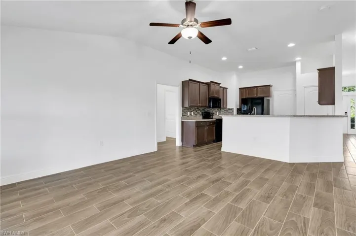 Unfurnished living room with ceiling fan, recessed lighting, vaulted ceiling, and light wood finished floors