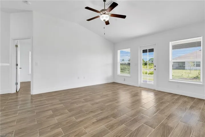 Spare room featuring lofted ceiling, ceiling fan, and light wood-style flooring