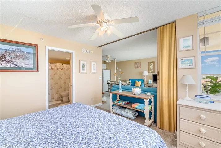 Bedroom featuring ceiling fan, white refrigerator, light colored carpet, and a textured ceiling