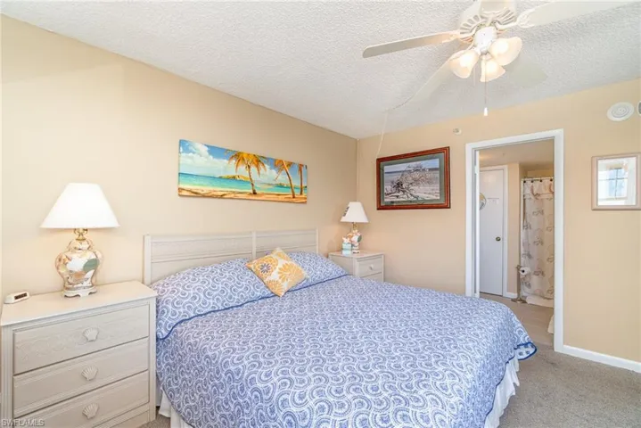 Bedroom with a textured ceiling, ceiling fan, and light colored carpet