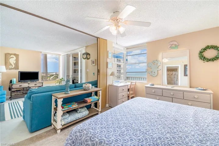 Carpeted bedroom featuring a textured ceiling, expansive windows, and ceiling fan