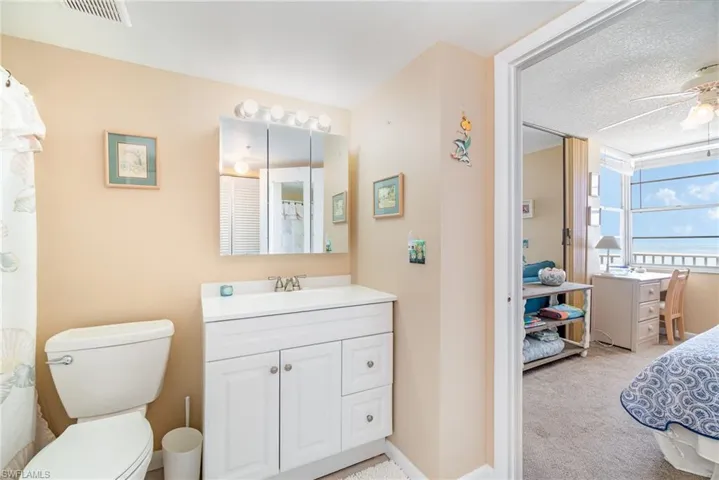 Bathroom featuring ceiling fan, a textured ceiling, vanity, and toilet