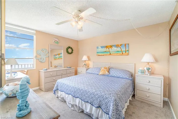 Bedroom featuring a textured ceiling, ceiling fan, and light carpet