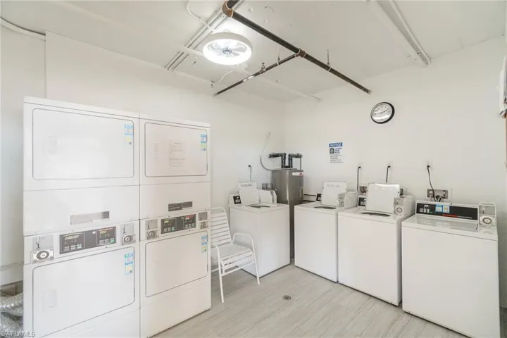 Laundry room with stacked washer and dryer, washing machine and dryer, and electric water heater