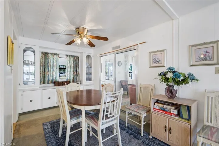Dining room with dark colored carpet and a ceiling fan
