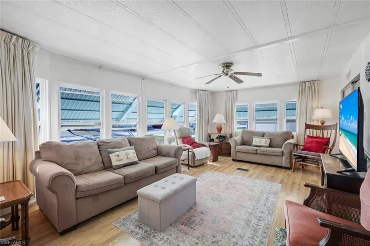 Living room with light wood finished floors, a ceiling fan, and a textured ceiling
