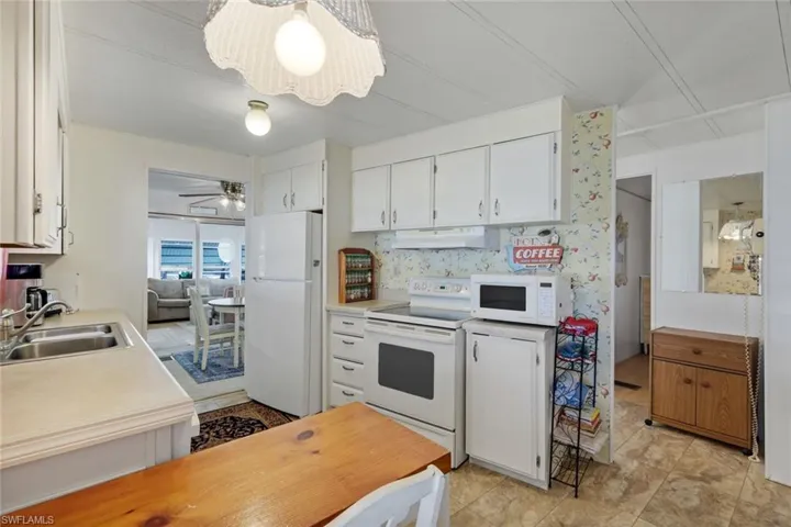 Kitchen with white cabinetry, white appliances, light countertops, and ceiling fan