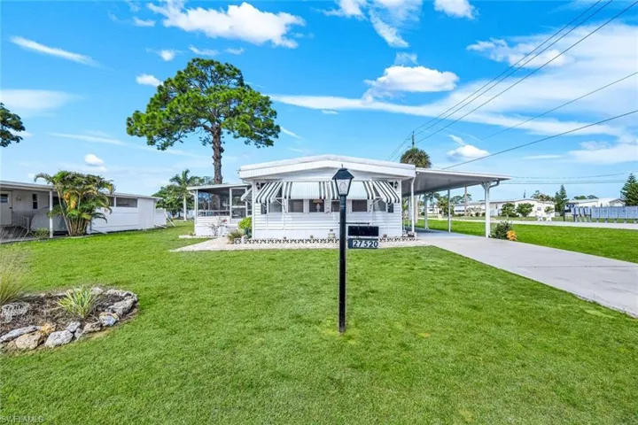 Manufactured / mobile home with an attached carport, a front yard, concrete driveway, a patio area, and a sunroom