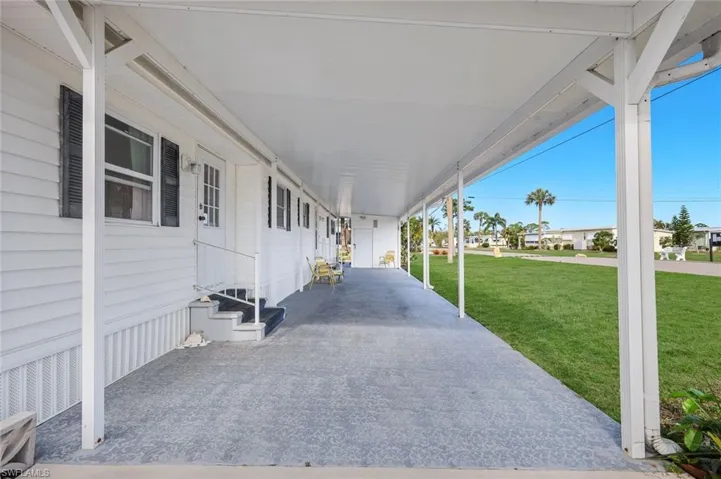 Porch with a yard, a residential view, entry steps, and a carport