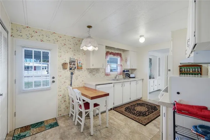 Kitchen with light countertops, white cabinetry, white appliances, decorative light fixtures, and a textured ceiling