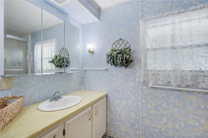 Bathroom featuring wallpapered walls and vanity