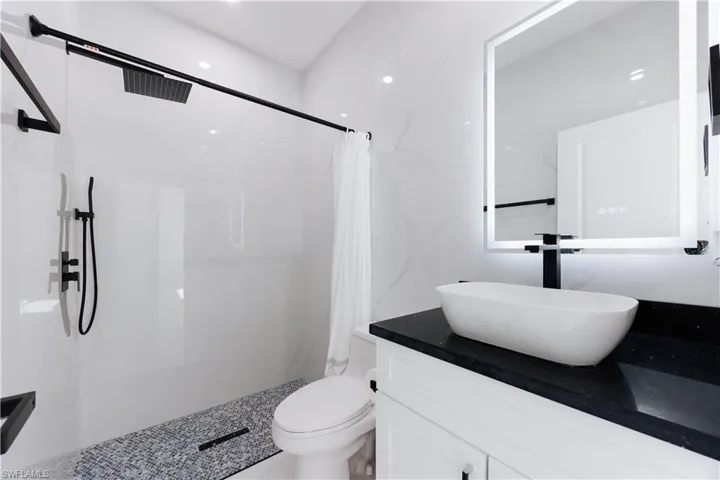 Bathroom featuring vanity, toilet, and curtained shower