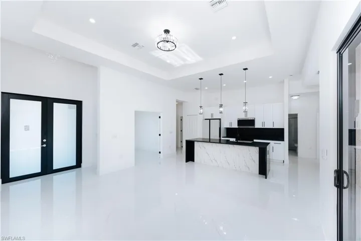 Kitchen with an inviting chandelier, white cabinetry, hanging light fixtures, and a tray ceiling