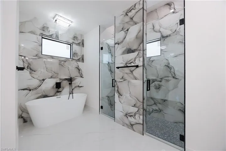 Bathroom featuring separate shower and tub, a wealth of natural light, and tile walls