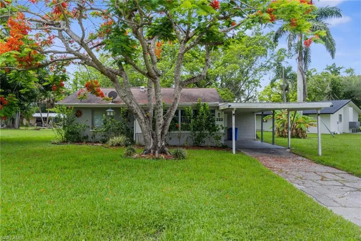 Single story home featuring a front yard, asphalt driveway, and an attached carport