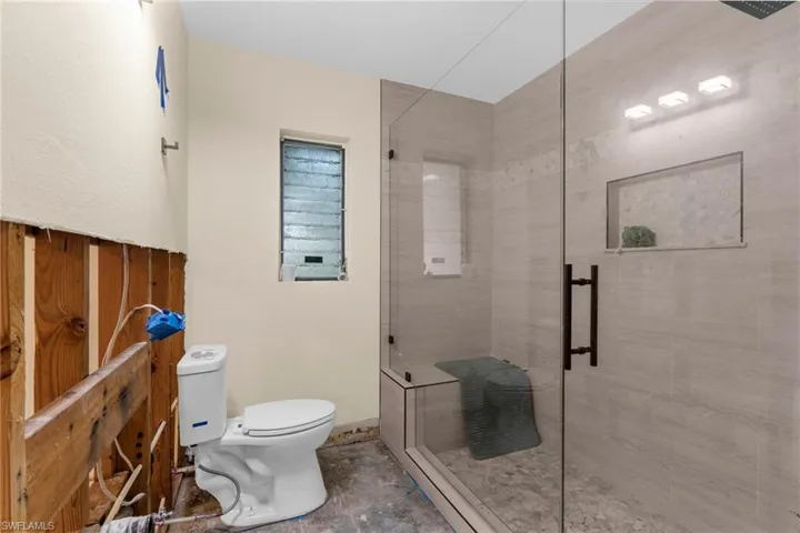 Full bath featuring toilet and a shower stall