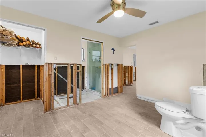 Bathroom with wood finished floors, a ceiling fan, and toilet
