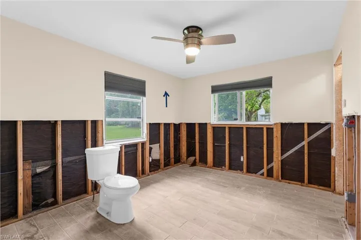 Bathroom with toilet, ceiling fan, and wood finished floors
