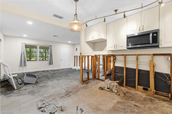 Kitchen with stainless steel microwave, pendant lighting, recessed lighting, and white cabinetry