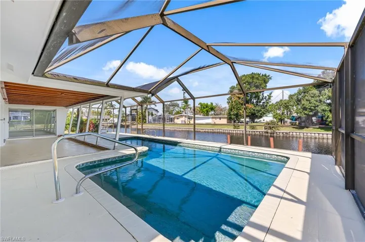 Screened-in pool deck featuring an in-ground swimming pool with handrails