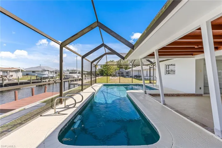Screened-in outdoor living space featuring a rectangular pool, integrated spa, and a concrete patio