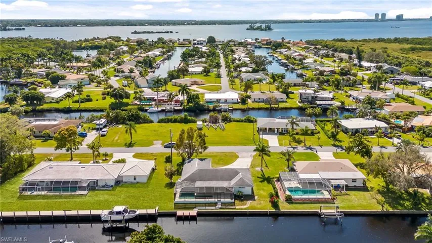 Waterfront community featuring canal access, mature landscaping, and an open water backdrop
