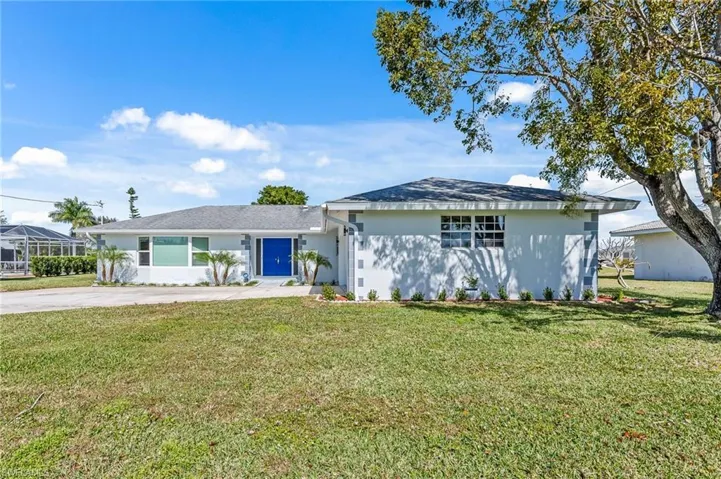 Single-story residence featuring a white stucco exterior with gray corner accents, a gray shingle roof, and a vibrant blue double entry door