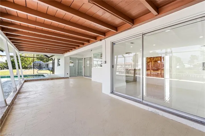 Expansive covered patio featuring a wood-finish ceiling, large format concrete-style flooring, and multiple sets of sliding glass doors
