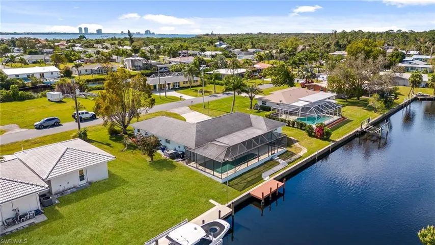 Waterfront property featuring a private boat dock, screened-in pool enclosure, and mature landscaping