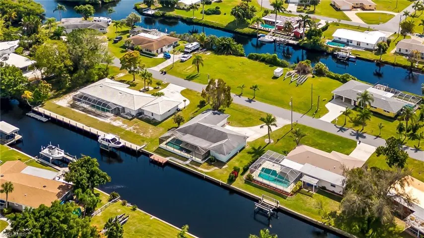 Waterfront property featuring a private boat dock, screened-in swimming pool, and mature palm trees