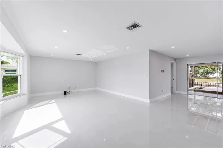 Spacious room with light gray walls, large bay window, recessed lighting, and expansive polished tile flooring