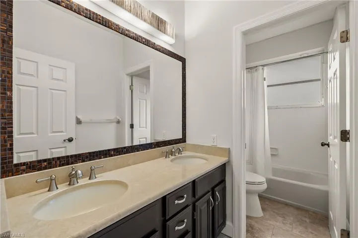 Full bath off bedroom #3 featuring double vanity and shower / bathtub combination with curtain